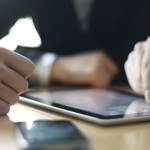 Trio sat at table with devices on desk