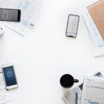 Mobile devices laid out on a desk with coffee cup and papers