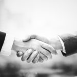 Greyscale image of two adults shaking hands